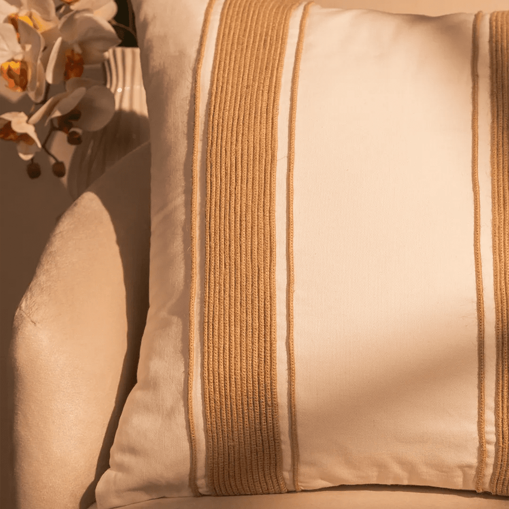 Capa de almofada decorativa no tamanho 50x50 cm na cor branca confeccionada em algodão sustentável com bordados rústicos de juta natural com fechamento em zíper invisível, sinônimo de bem-estar e conforto térmico, ideal para momentos de descanso e relaxamento no lar.