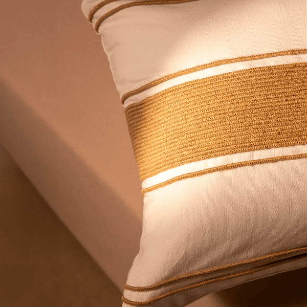 Capa de almofada decorativa no tamanho 40x60 cm na cor branca confeccionada em algodão sustentável com bordados rústicos de juta natural com fechamento em zíper invisível, ideal para complementar jogos de cama ou sofás, aliando conforto ergonômico e design moderno.